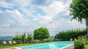 A rectangular swimming pool with a brick border, surrounded by a grassy area and a wooden fence. - Holiday Home Monte Santa Maria Pool Retreat (Monte Santa Maria Tiberina)