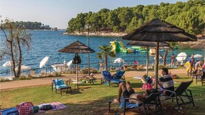 A beachside area with lounge chairs, umbrellas, and a water slide. - Peaceful House Only 900m From the sea With Swimming Pool, Bbq, Wifi, Airco (Tar-Vabriga)