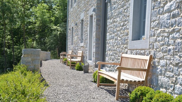 A stone building with a gravel pathway leading to wooden benches. - Peaceful Forest Stay in Gesves (Gesves)