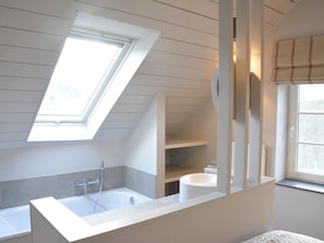 A modern bathroom with a skylight, a bathtub, a toilet, and a window with a striped blind. - Peaceful Forest Stay in Gesves (Gesves)