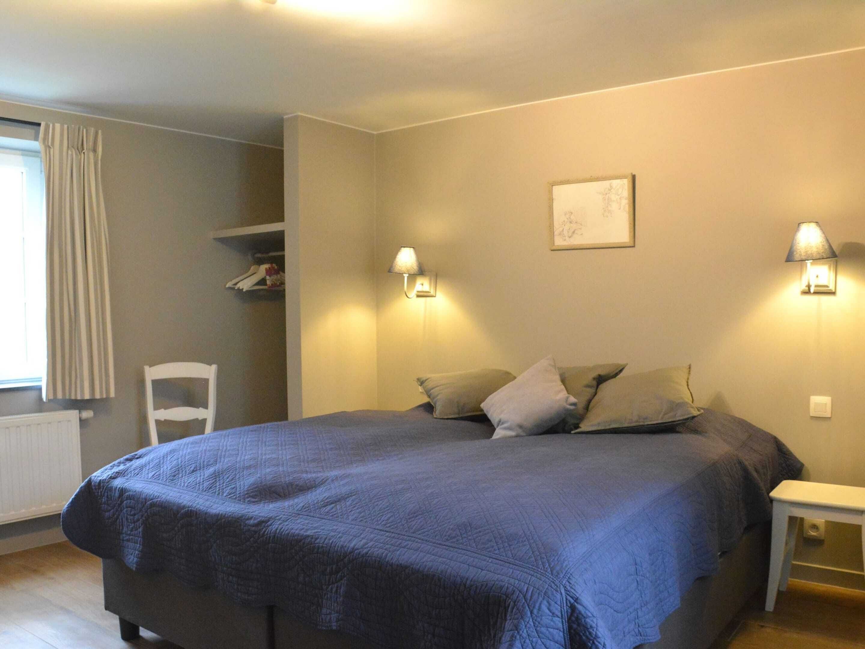 Un dormitorio con una cama grande, dos lámparas de noche, una silla y un radiador.