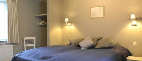 Un dormitorio con una cama grande, dos lámparas de noche, una silla y un radiador.