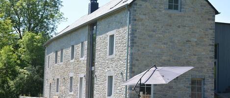 A stone building with a large patio area, outdoor seating, and a chimney.