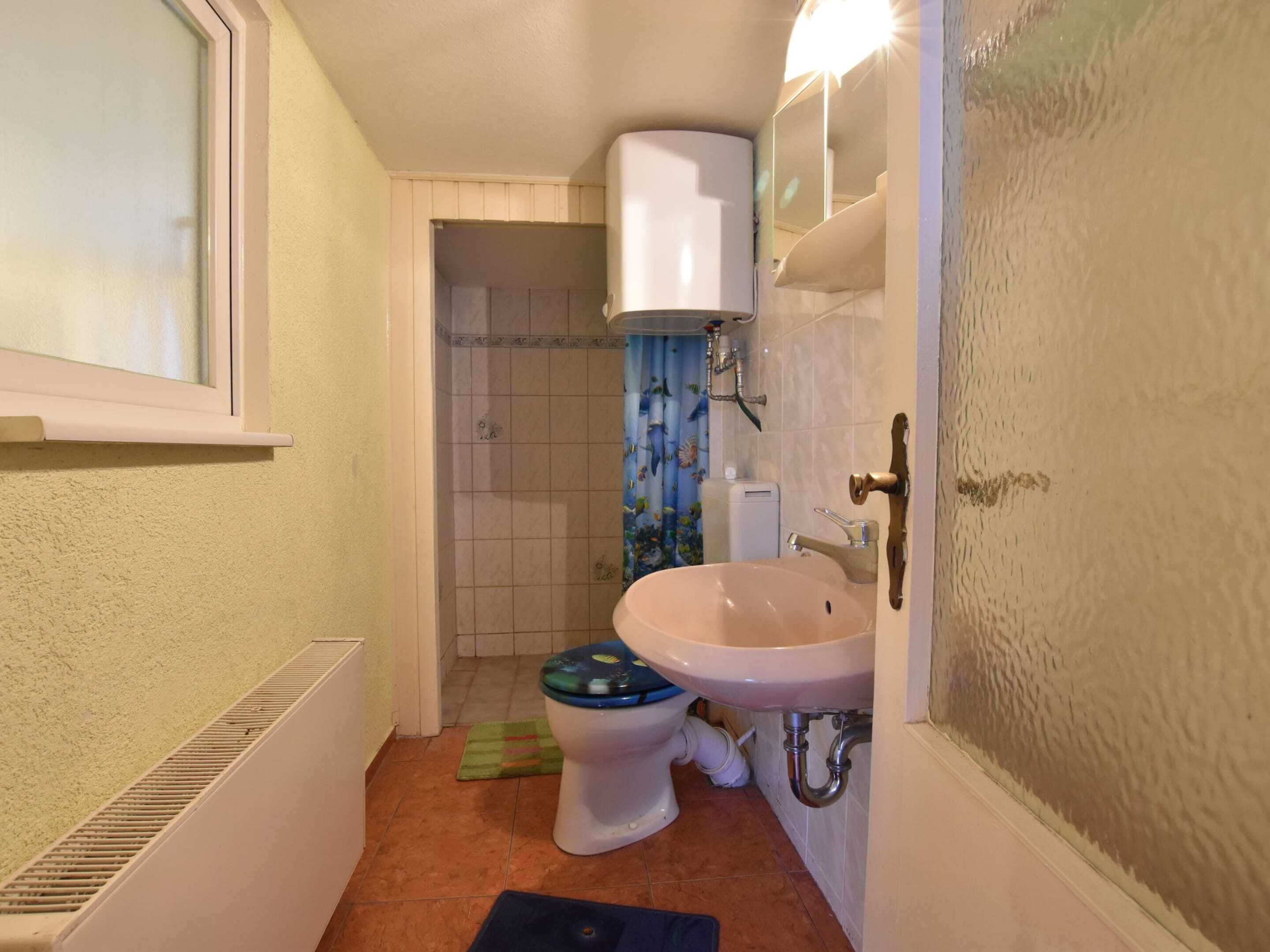 Un baño pequeño con inodoro, lavamanos y zona de ducha.