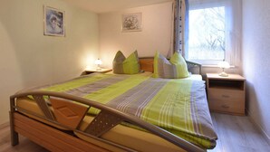 A bedroom with a bed, two bedside tables, a window with curtains, and two wall-mounted pictures. - Cozy Apartment in Boltenhagen Germany near Beach (Boltenhagen)