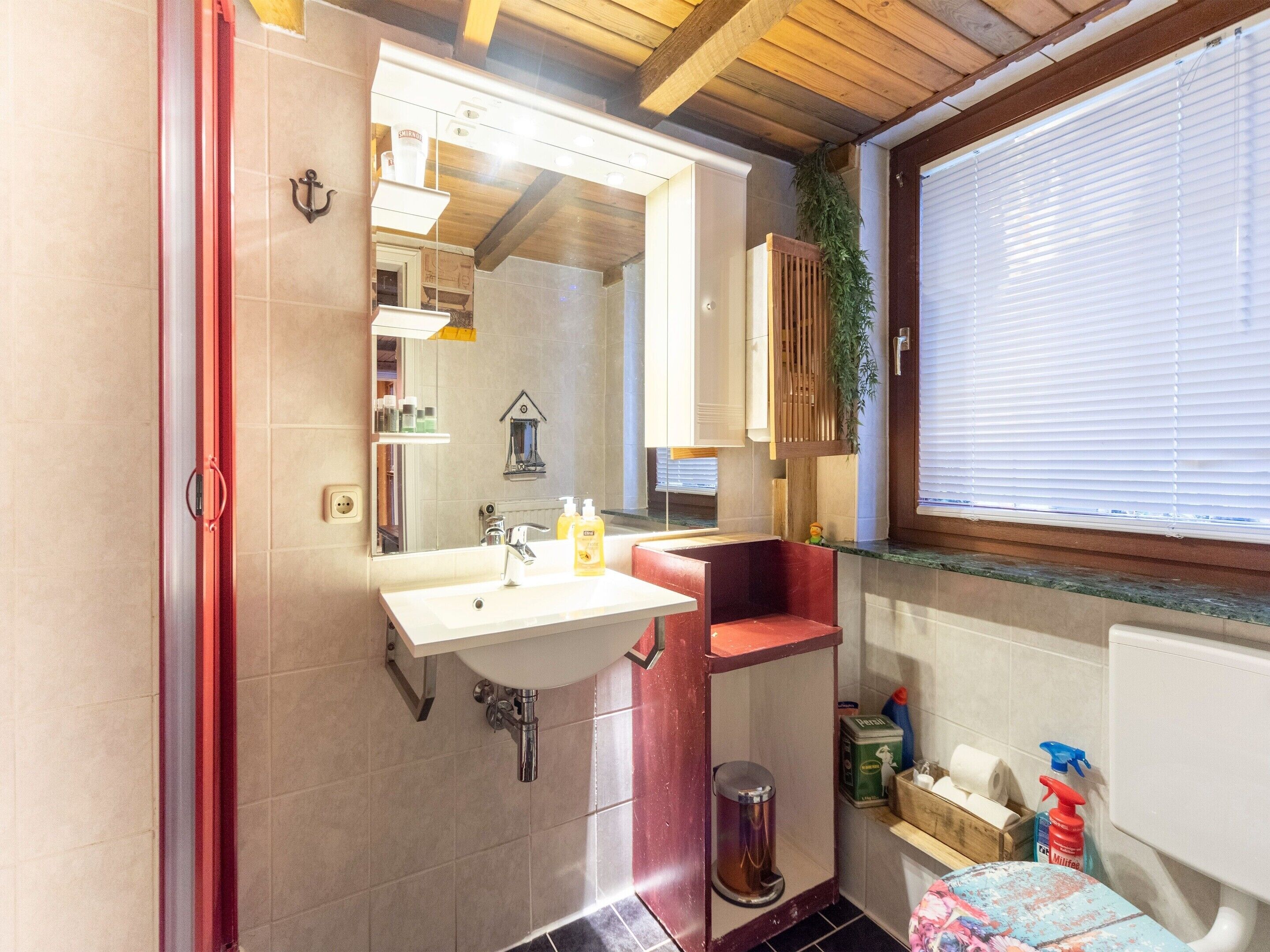 Une petite salle de bain avec un lavabo, un miroir et une fenêtre.