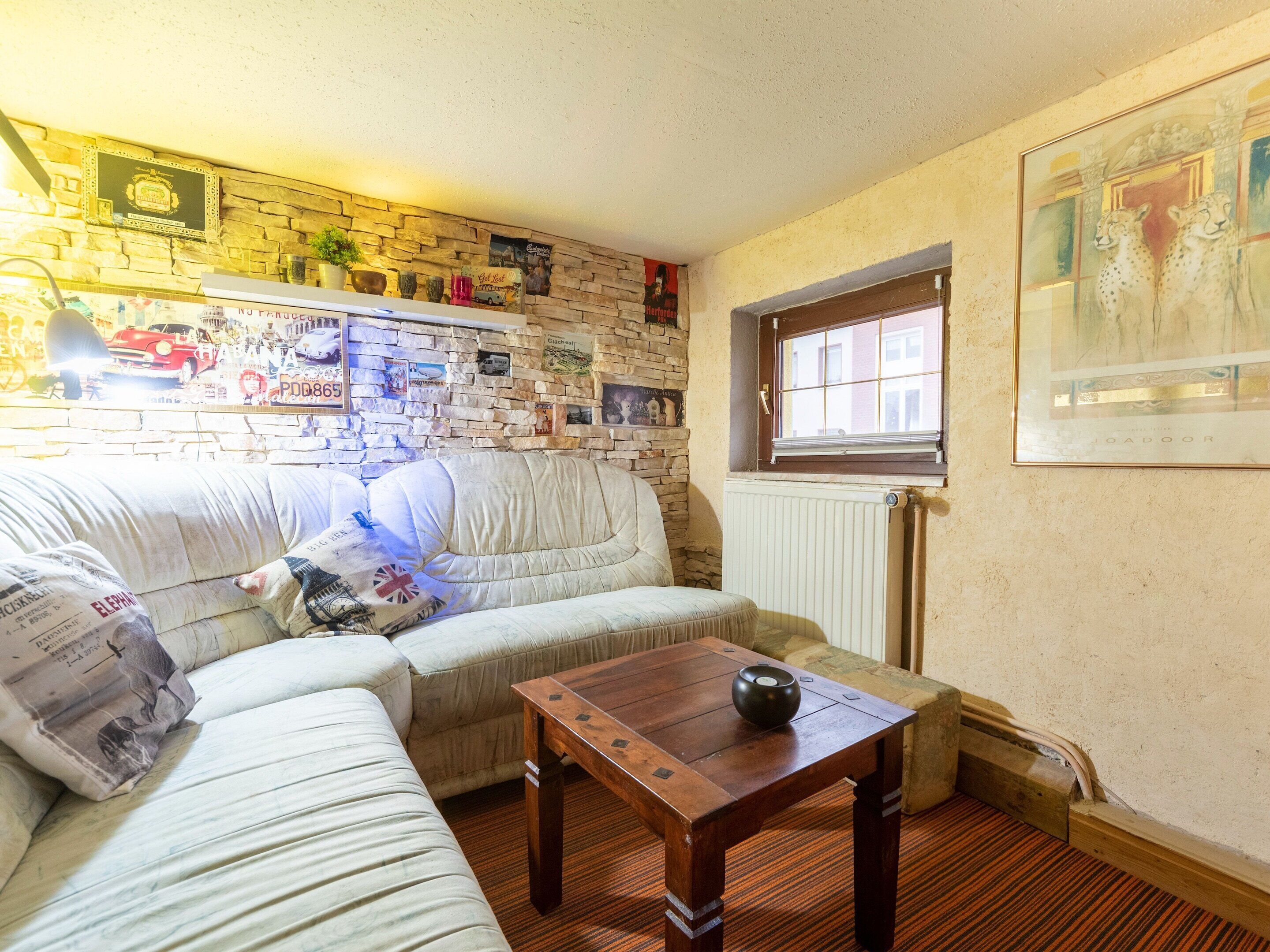 A cozy living room with a stone wall, a wooden table, and a window.