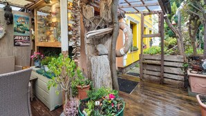 A rustic outdoor seating area with wooden furniture and potted plants. - Charmante Ferienwohnung in Wismar mit Garten (Wismar)
