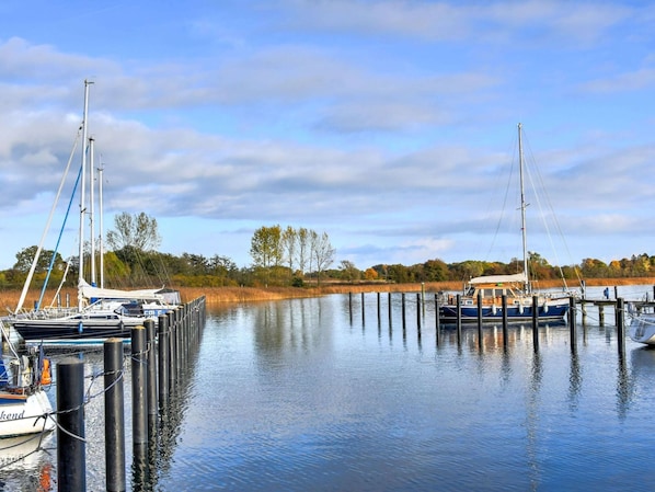A marina with several boats docked, calm water, and a clear sky.