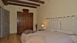 Ein Schlafzimmer mit einem großen Bett, einem Holzschrank und einem Nachttisch mit Lampe.