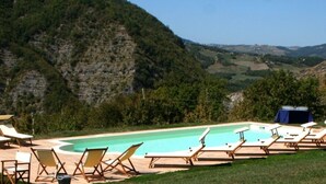 Ein Poolbereich mit Liegestühlen und einem Pool, umgeben von einer gebirgigen Landschaft.