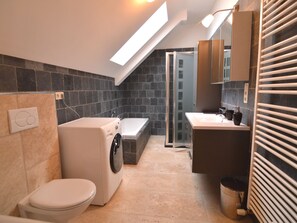 Un baño moderno con lavadora, bañera y retrete.
