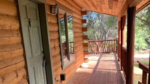 A wooden cabin with a porch, a door, and a window.