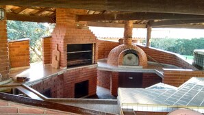 A brick-built outdoor kitchen with a pizza oven and a grill, surrounded by a covered patio area. - Chácara Vale da Esperança 40 minutes from São Paulo with Fiber Internet (Mairinque)
