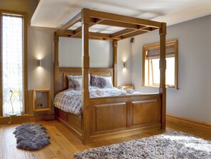 Un lit à baldaquin avec une structure en bois, une couvre-lit à motifs et deux tables de chevet avec des lampes.