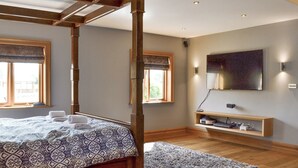 A bedroom with a four-poster bed, a television mounted on the wall, and a wooden shelf with electronic devices. - 5 bedroom accommodation in Stalmine, near Poulton-le-Flyde (Stalmine, near Poulton-le-Flyde)