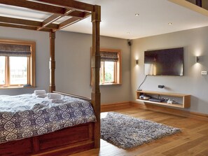A bedroom with a four-poster bed, a television mounted on the wall, and a wooden shelf with electronic devices. - 5 bedroom accommodation in Stalmine, near Poulton-le-Flyde (Stalmine, near Poulton-le-Flyde)