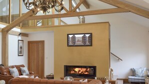 A spacious living room with a fireplace, a brown leather sofa, and a wooden staircase. - 5 bedroom accommodation in Stalmine, near Poulton-le-Flyde (Stalmine, near Poulton-le-Flyde)