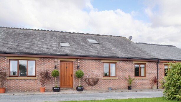 A brick building with a wooden door, windows, and potted plants. - 5 bedroom accommodation in Stalmine, near Poulton-le-Flyde (Stalmine, near Poulton-le-Flyde)