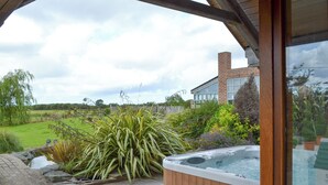 A hot tub in a garden with a wooden pergola, a brick house in the background, and a grassy field. - 5 bedroom accommodation in Stalmine, near Poulton-le-Flyde (Stalmine, near Poulton-le-Flyde)