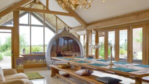 A spacious room with a high ceiling, large windows, a wooden bench, and a hanging chair. - 5 bedroom accommodation in Stalmine, near Poulton-le-Flyde (Stalmine, near Poulton-le-Flyde)