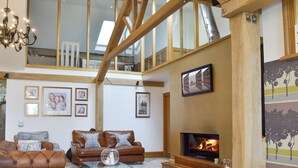 A spacious living room with a fireplace, leather sofas, and a glass coffee table. - 5 bedroom accommodation in Stalmine, near Poulton-le-Flyde (Stalmine, near Poulton-le-Flyde)