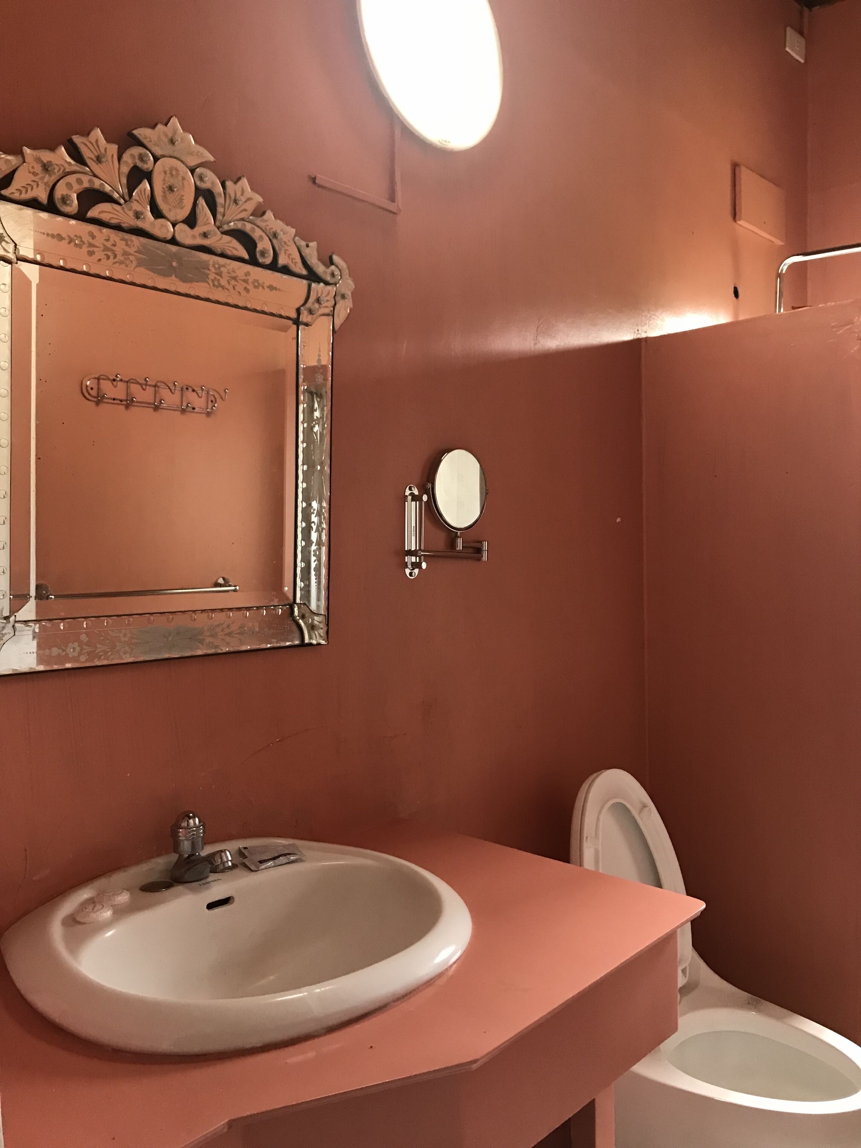 Une salle de bain avec un lavabo rose, un miroir et des toilettes.