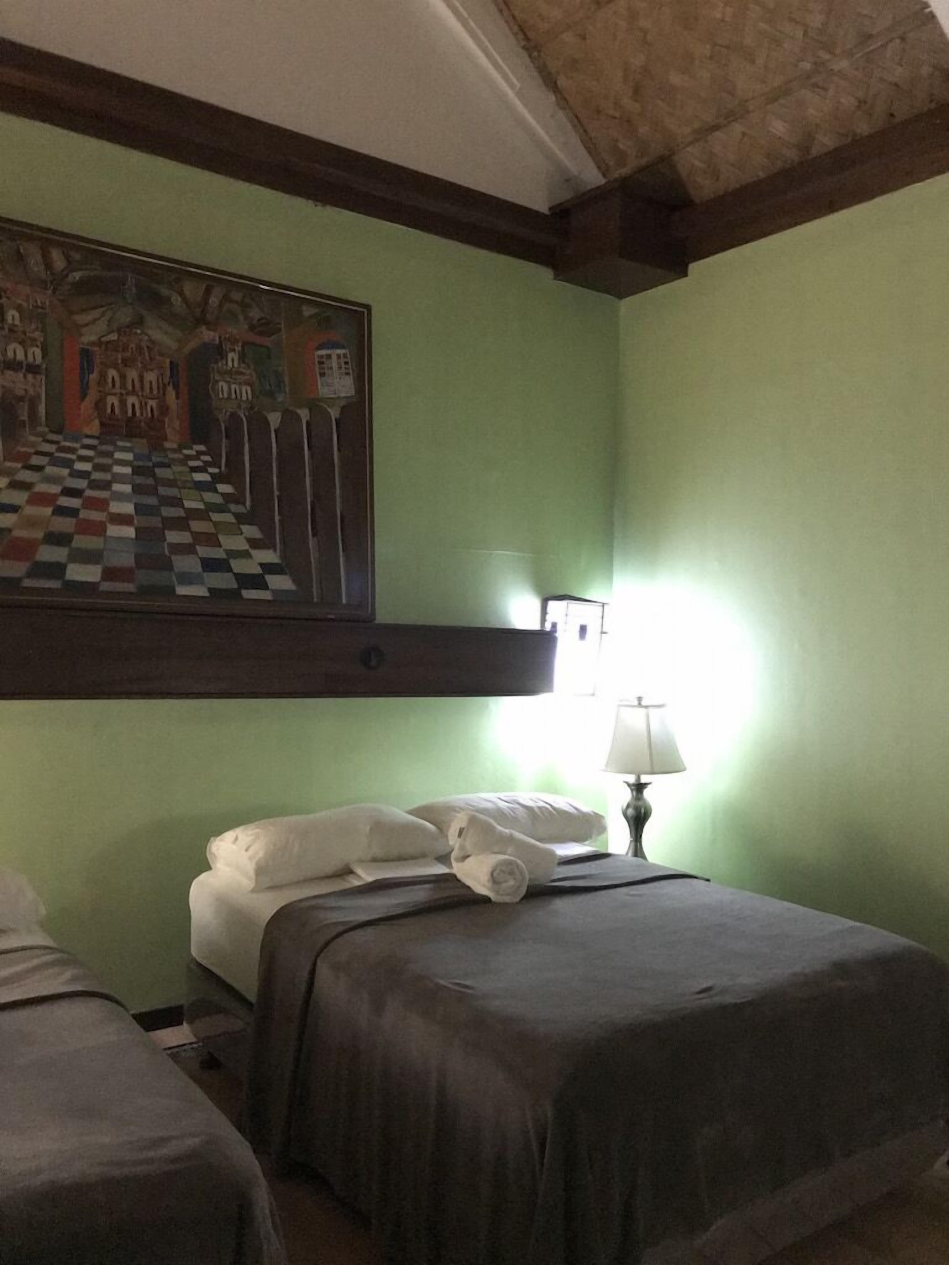 Ein Hotelzimmer mit zwei Betten, einem Schachbrettmuster-Bodenbelag, einem Schlossgemälde und einer Lampe.