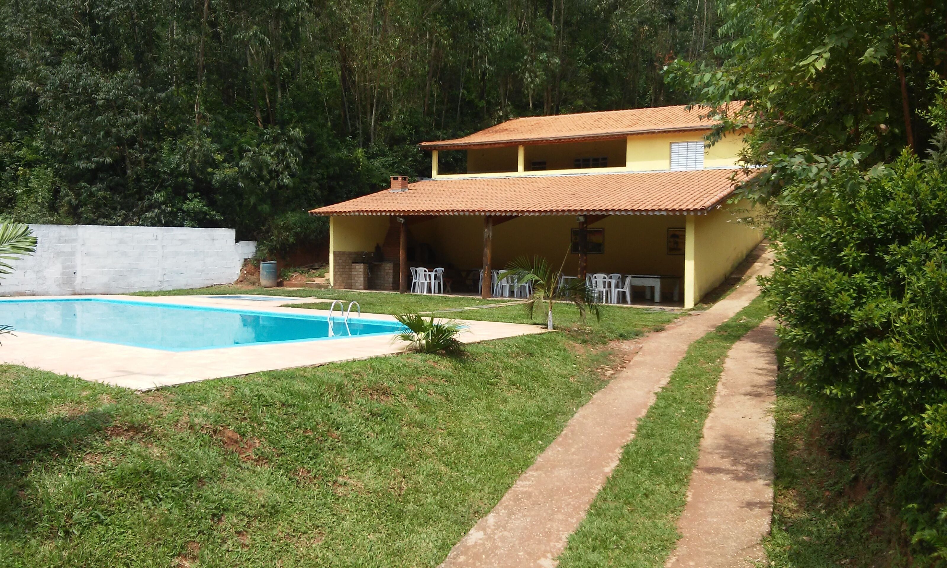 A two-story house with a swimming pool, a covered patio, and a garden.