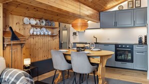 Une cuisine chaleureuse avec des murs en bois, une table à manger avec des chaises et des appareils électroménagers modernes.