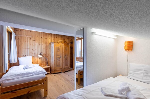 A room with two wooden beds, a wardrobe, and a bedside lamp. - App. Les Lupins 17 - Two Bedroom Apartment, Sleeps 4 (Riddes)