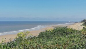 A coastal landscape with a beach, ocean, and a distant pier. - 2 bedroom accommodation in East Runton, near Cromer (East Runton, near Cromer)