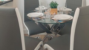 A dining table set for four with clear glassware and plates, surrounded by modern chairs. - 2 bedroom accommodation in East Runton, near Cromer (East Runton, near Cromer)