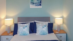 A neatly made bed with two pillows, two bedside lamps, and a small nightstand with a magazine. - 2 bedroom accommodation in East Runton, near Cromer (East Runton, near Cromer)