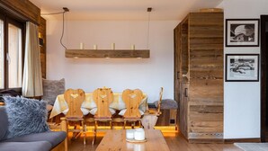 A cozy living room with a wooden sofa, a wooden dining table, and a bench with heart-shaped cutouts.