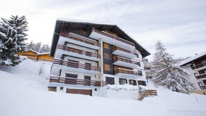 A multi-story hotel with balconies, surrounded by snow-covered trees.