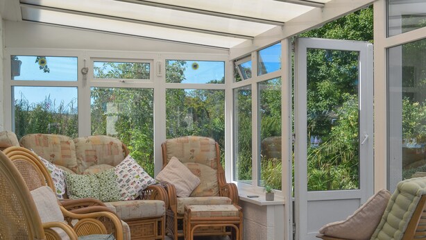 A conservatory with wicker furniture, large windows, and a view of greenery. - 4 bedroom accommodation in Goathland (Goathland)