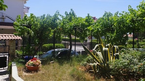 A residential area with a white building, a parked car, and a garden with various plants. - Boutique Apartment in Pjescana Uvala With Balcony (Medulin)