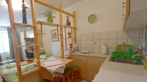 A compact kitchen with a dining area, featuring a wooden partition, a small table with chairs, and a refrigerator. - Boutique Apartment in Pjescana Uvala With Balcony (Medulin)