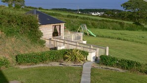 A wooden cabin with a balcony overlooking a grassy area and a body of water. - RUSTIC LOG CABIN LOCATED GREENCASTLE CO DONEGAL (Greencastle)