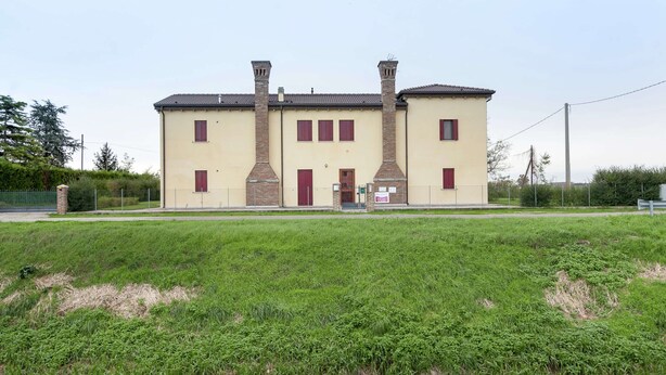 A two-story building with a symmetrical facade, featuring a central entrance with a door and windows on either side.