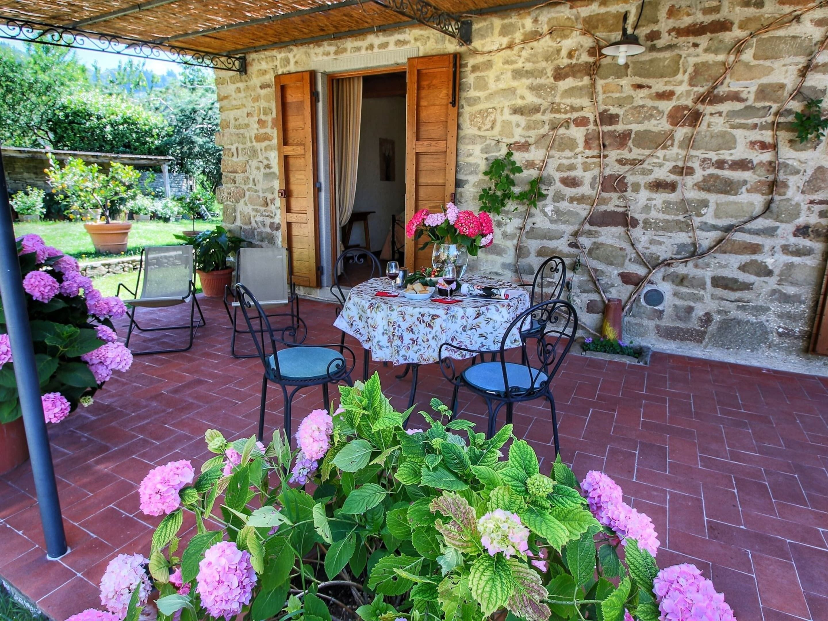 A patio with a round table, chairs, and a potted plant.