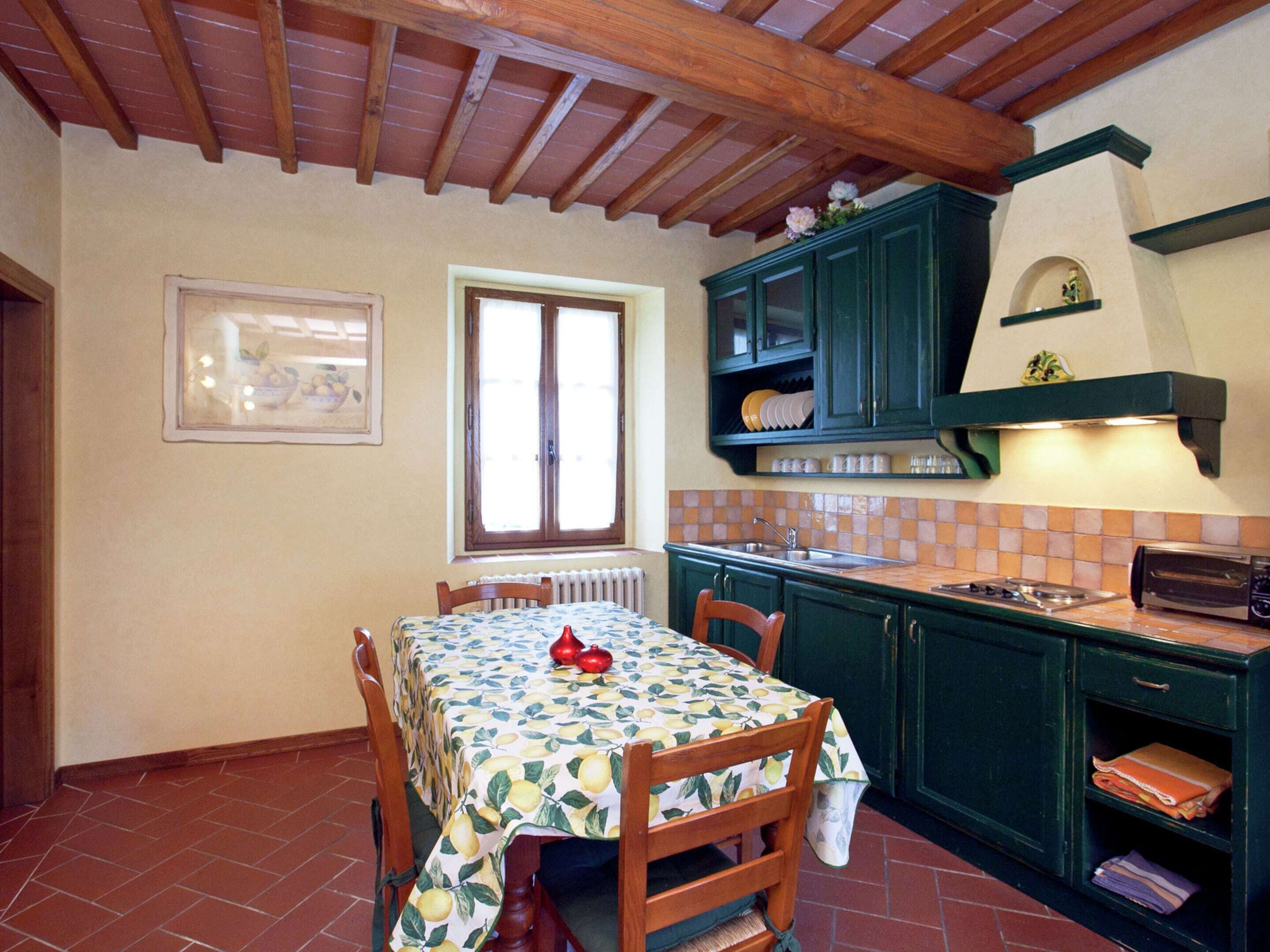 A kitchen with a dining table, chairs, a window, and green cabinets.