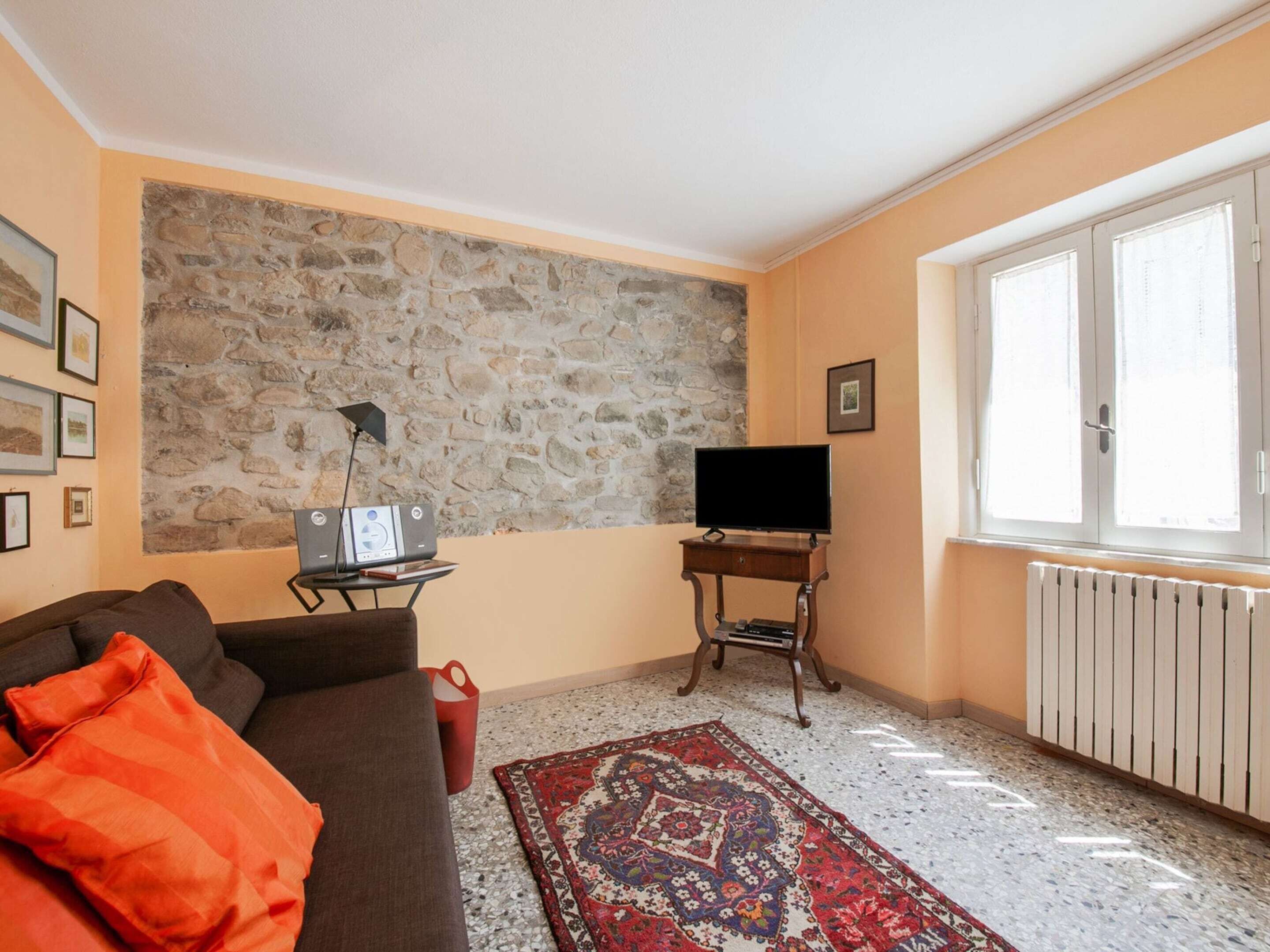 A living room with a stone wall, a television, a sofa, and a radiator.