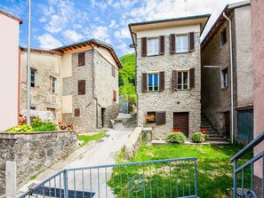 A narrow street with stone buildings, a metal staircase, and a small garden area. - Holiday Home in Pascoso Near Forest (Pescaglia)