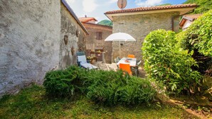 A courtyard with stone buildings, a table with chairs, and a satellite dish. - Holiday Home in Pascoso Near Forest (Pescaglia)