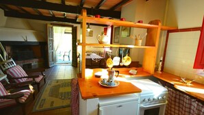 Une cuisine chaleureuse avec un plan de travail en bois, des appareils électroménagers blancs et un plafond rustique.