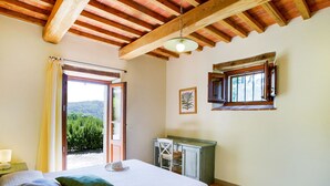 A bedroom with a bed, a desk, a chair, a window, and a view of greenery outside. - Belvilla by Oyo Erica (Anghiari)