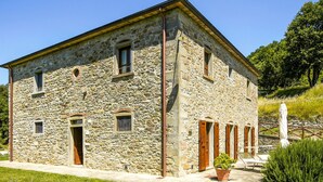 A stone building with a flat roof, multiple windows, and a door. - Belvilla by Oyo Erica (Anghiari)