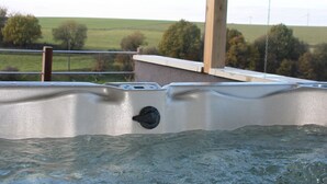 A hot tub with a view of a green landscape and a wooden structure in the background. - Luxury Cottage in Vaux-sur-Sûre with Hot Tub (Vaux-sur-Sure)